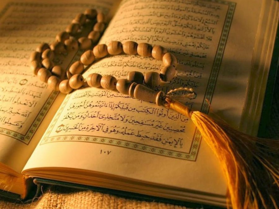 A copy of the Holy Quran open, with a tasbeeh resting on the page