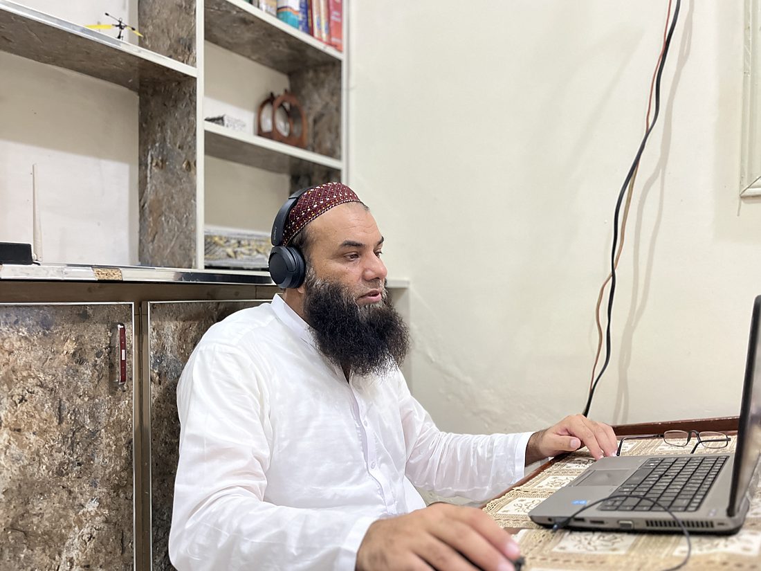 Qari Muhammad Naveed Raja working through a lesson at his desk, the Quran open on his screen