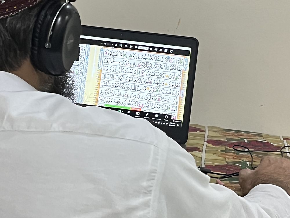 A live online Quran lesson in progress, a page of the Holy Quran shared on the teacher’s screen