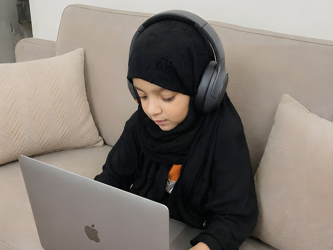 A young student reading from the laptop during her lesson