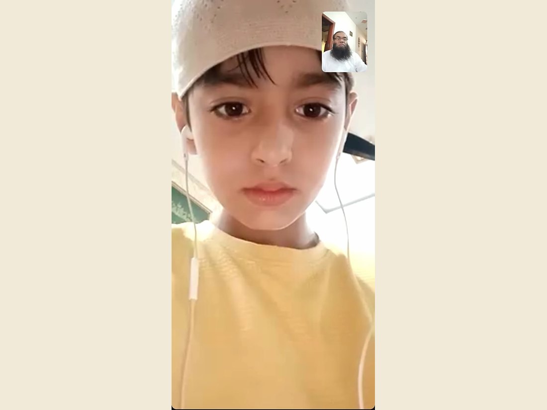 A Quran lesson on a video call, the student reciting and his teacher listening in the corner of the screen