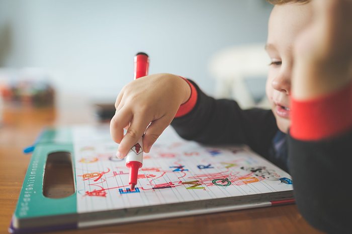 A boy writing English letters in his workbook, for the English classes